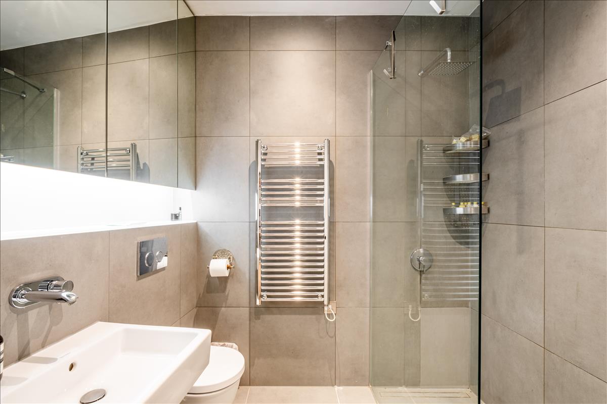 En-suite Bathroom - Set within a beautifully reimagined Victorian warehouse in the heart of Clerkenwell, this exceptional two-bedroom apartment combines industrial heritage with contemporary refinement. Occupying part of a thoughtfully converted late-19th-century building, the apartment extends to an impressive 1,368 sq ft, with soaring ceilings exceeding three metres, expansive factory-style glazing and carefully considered interiors throughout.