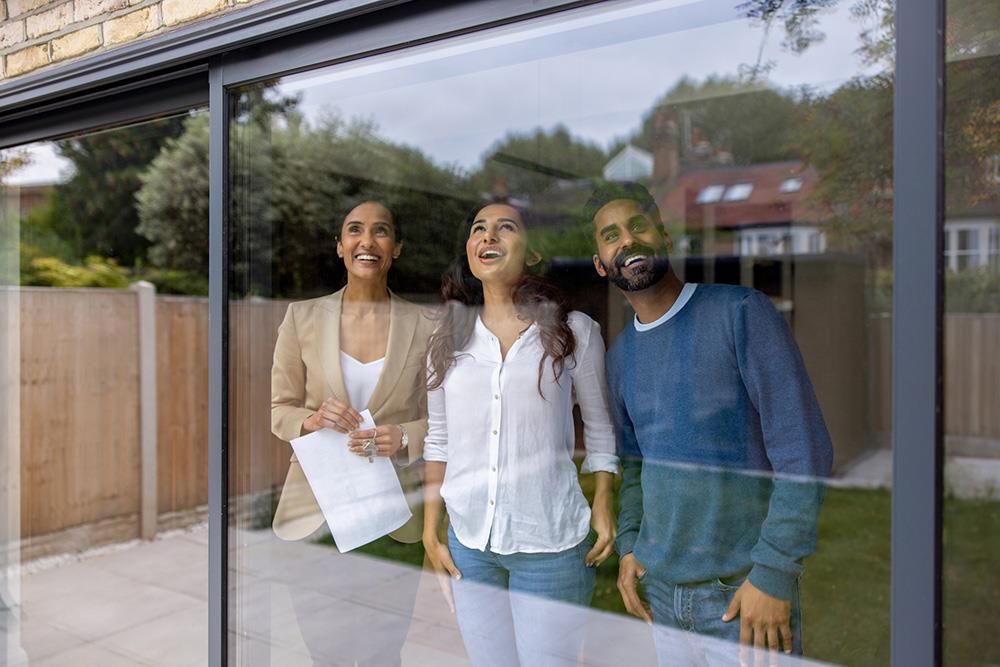 estate agent showing a house for rent to a happy couple and smiling
