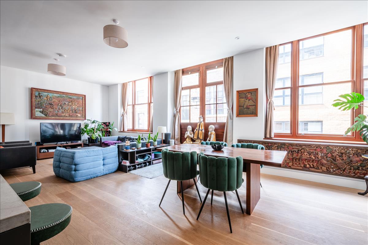 Living Room - Set within a beautifully reimagined Victorian warehouse in the heart of Clerkenwell, this exceptional two-bedroom apartment combines industrial heritage with contemporary refinement. Occupying part of a thoughtfully converted late-19th-century building, the apartment extends to an impressive 1,368 sq ft, with soaring ceilings exceeding three metres, expansive factory-style glazing and carefully considered interiors throughout.